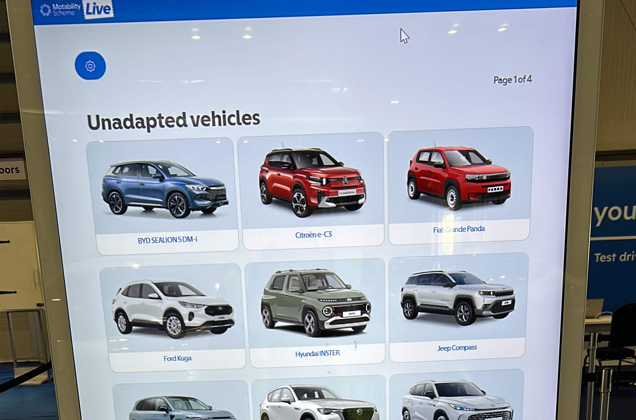 A digital screen at an event showing a list of cars that are available to test drive