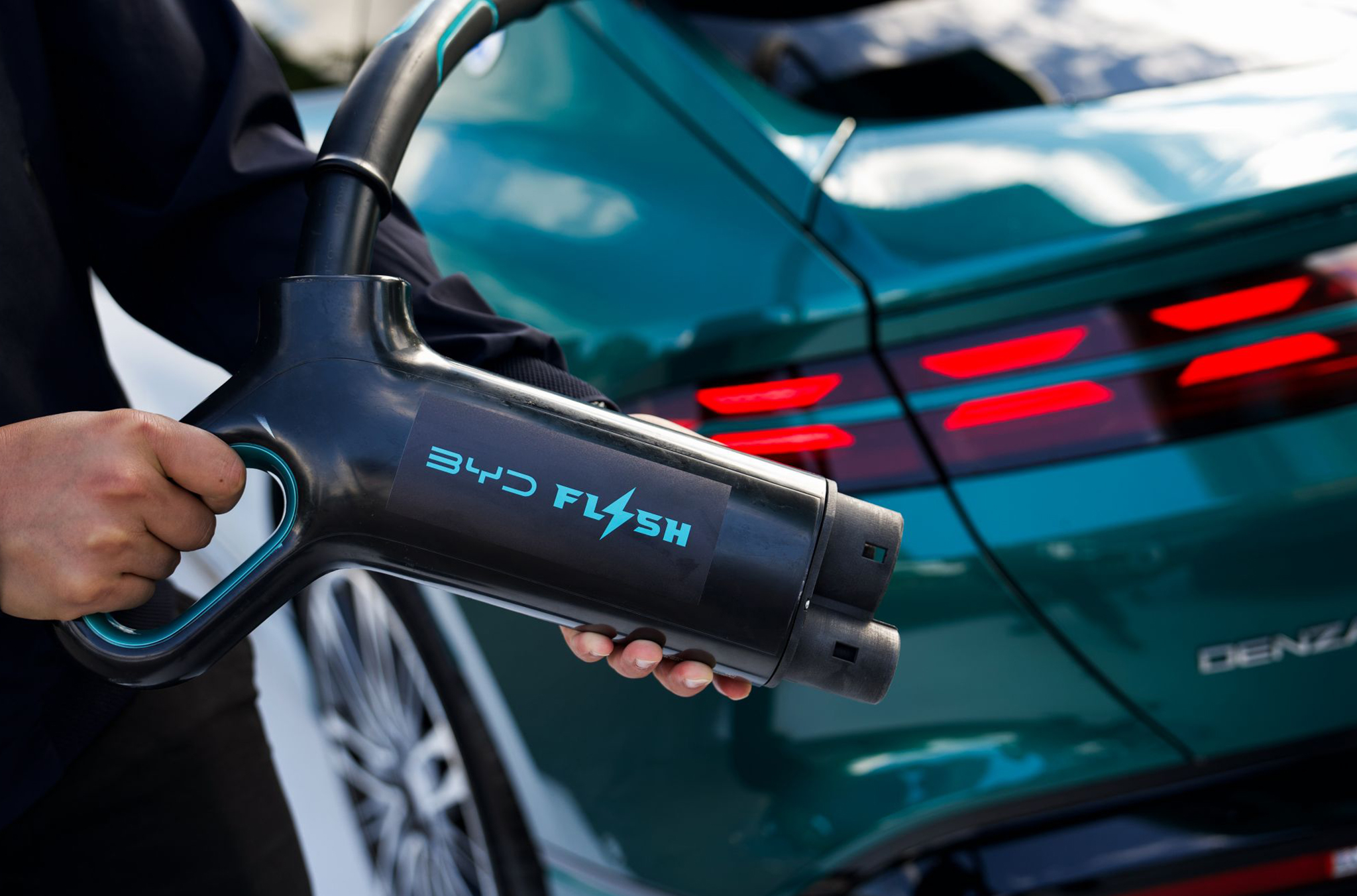 A person holding a DENZA Flash Charger